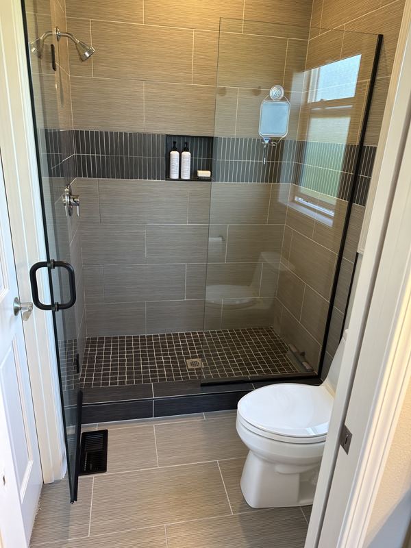 Walk-in tiled shower with glass door and mosaic floor
