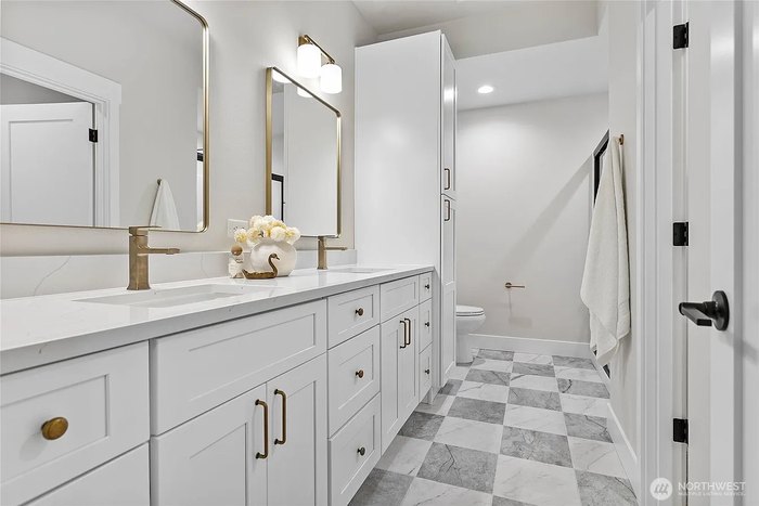 Double vanity with quartz counters and marble checkerboard floor