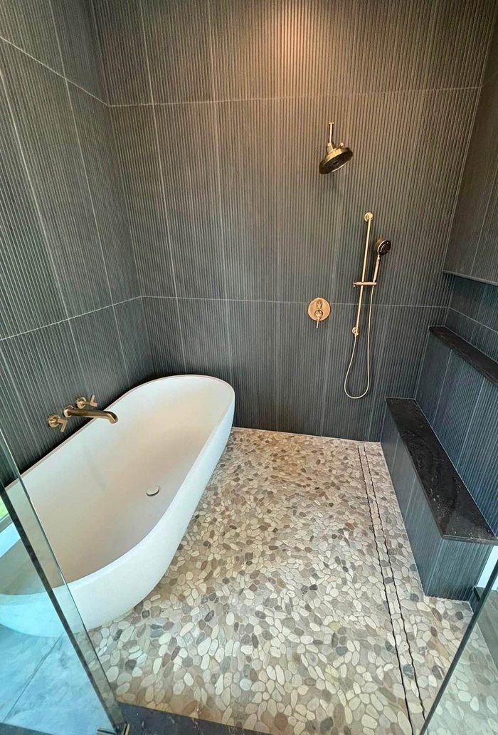 Wet room with freestanding tub, ribbed tile and pebble floor