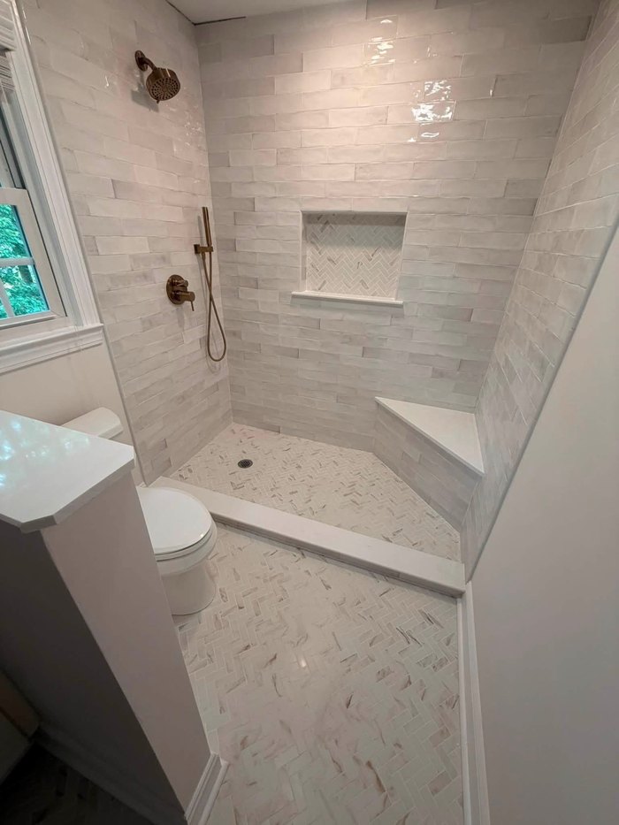 Tile shower with herringbone floor, niche and corner bench